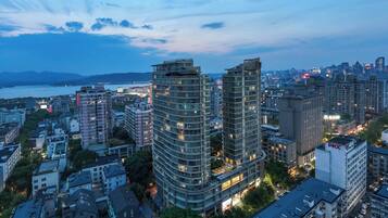 A high-rise building with multiple floors, surrounded by other buildings and a body of water in the background.