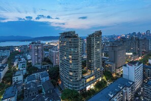 A high-rise building with multiple floors, surrounded by other buildings and a body of water in the background. - EVEN Hotel Hangzhou West Lake by IHG (Hangzhou)
