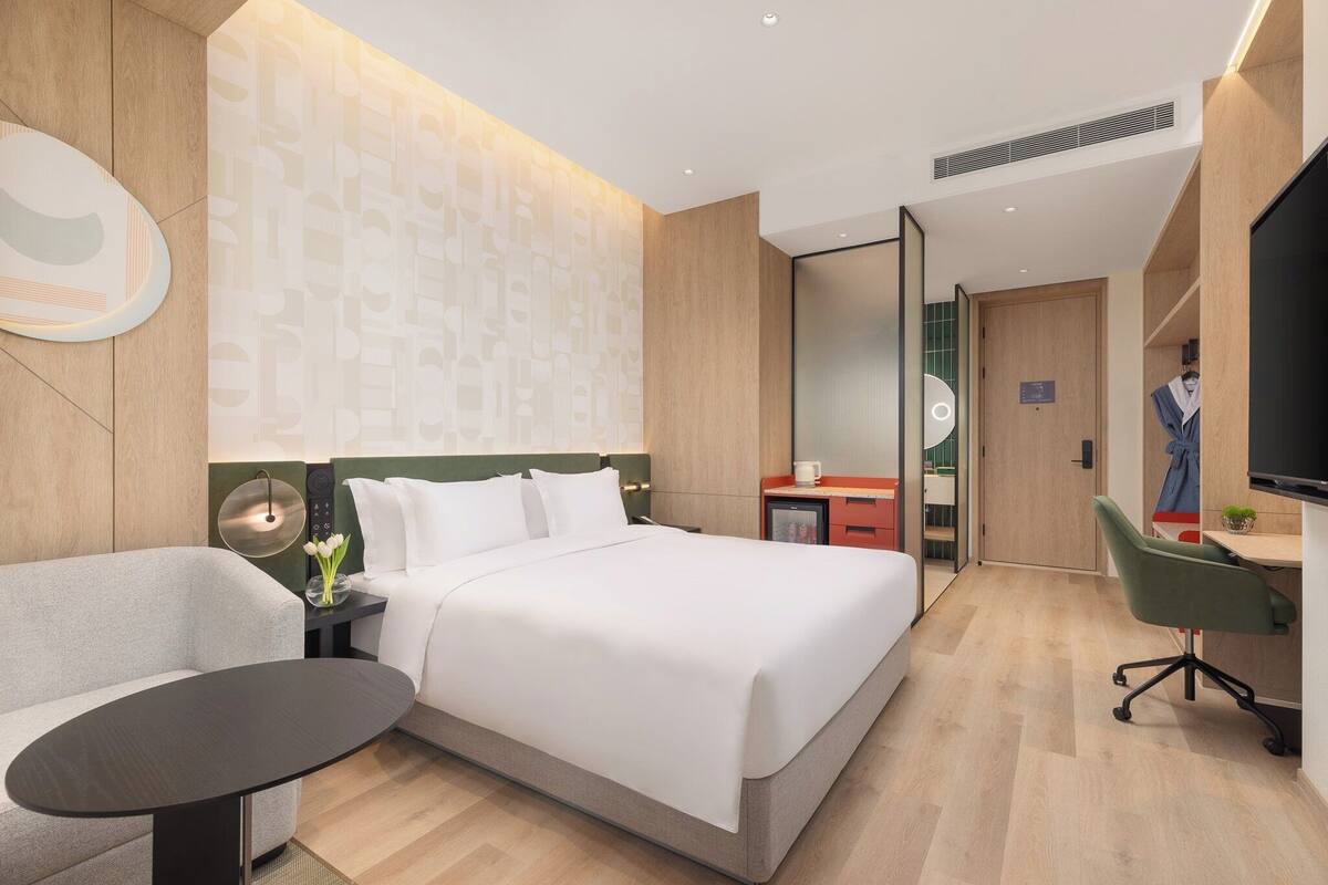 Una habitación de hotel moderna con una cama, un escritorio, una silla y un televisor.
