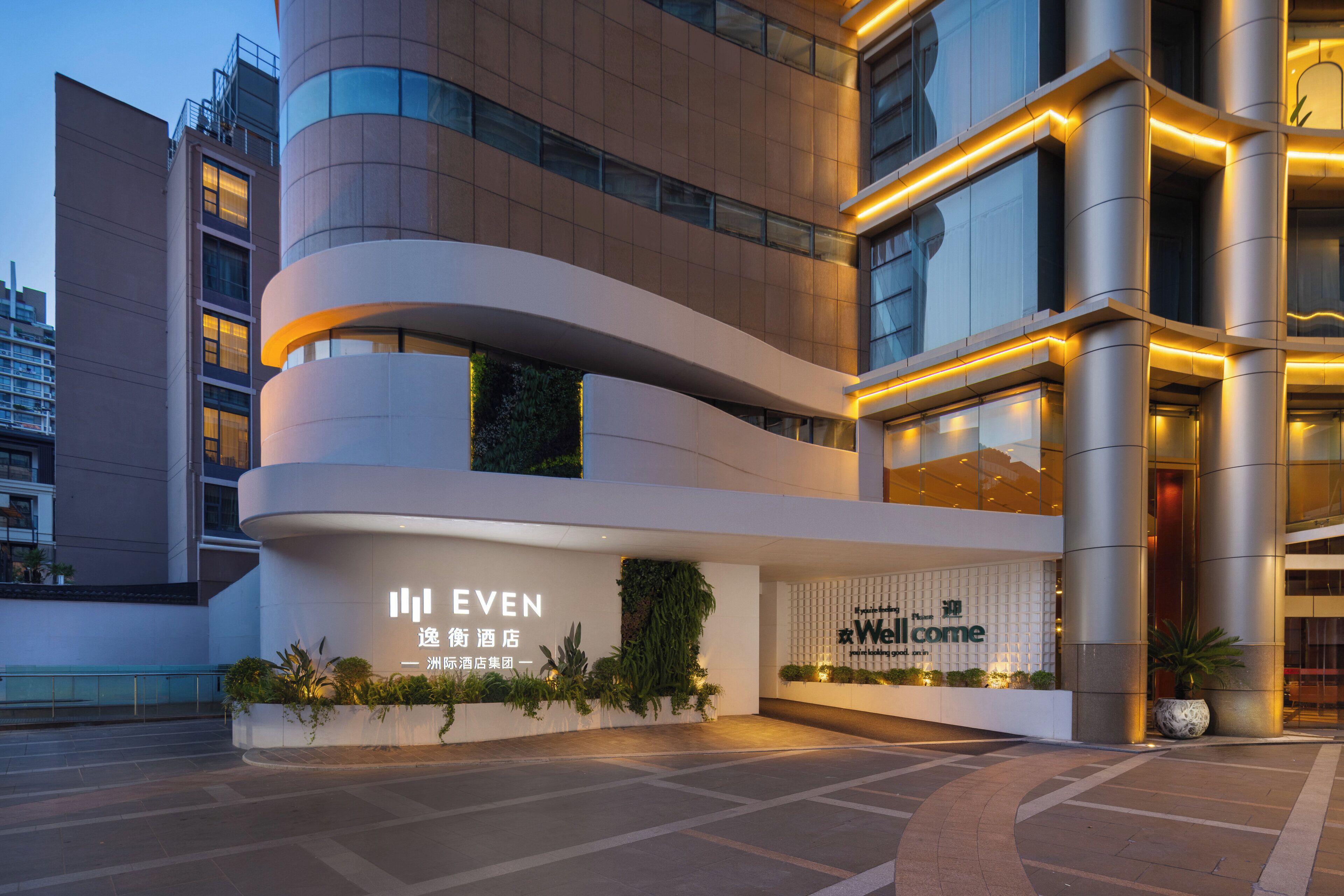 A modern hotel with a curved facade, large windows, and illuminated signage.
