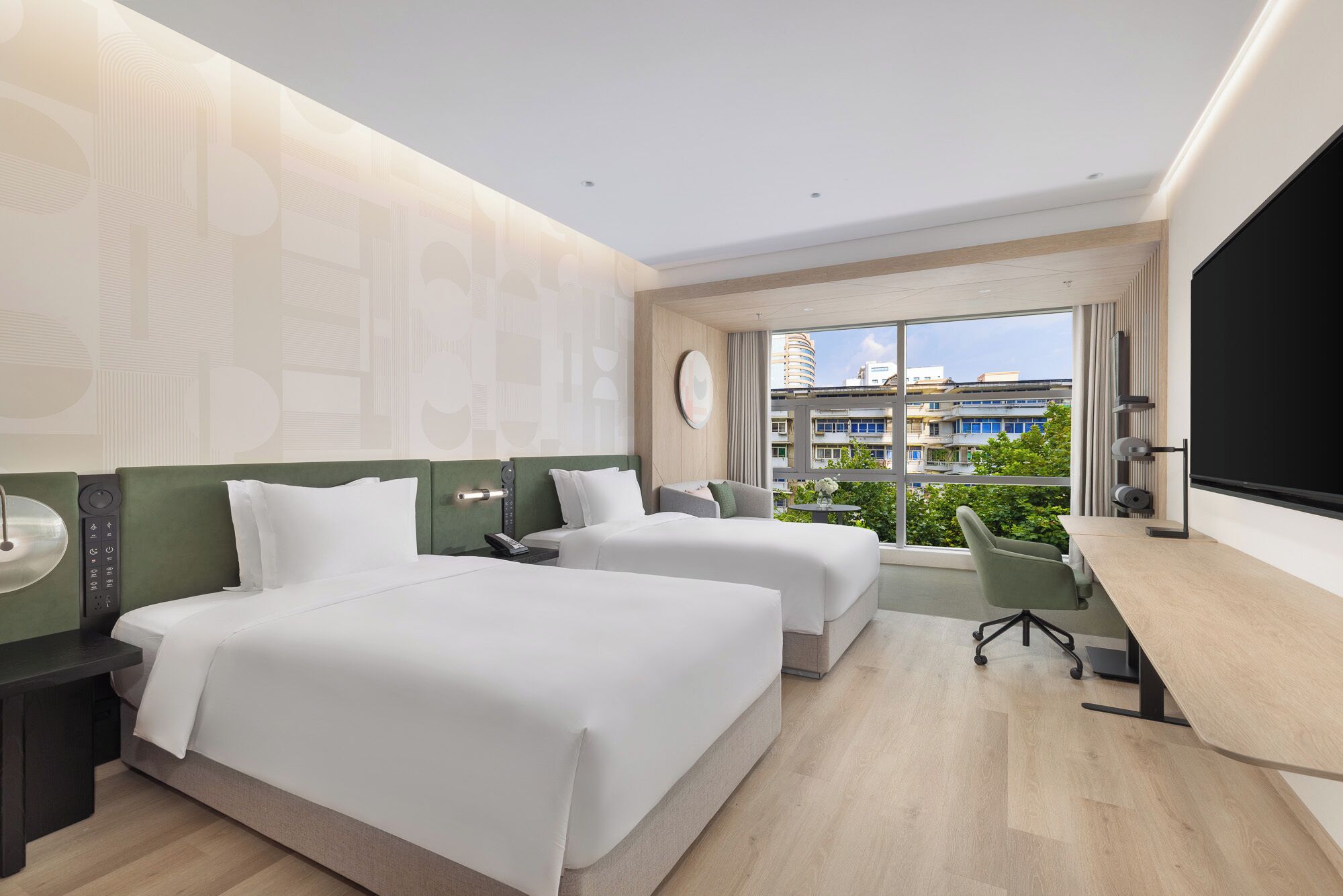 Una habitación de hotel moderna con dos camas, un escritorio y un ventanal que ofrece vistas a la ciudad.