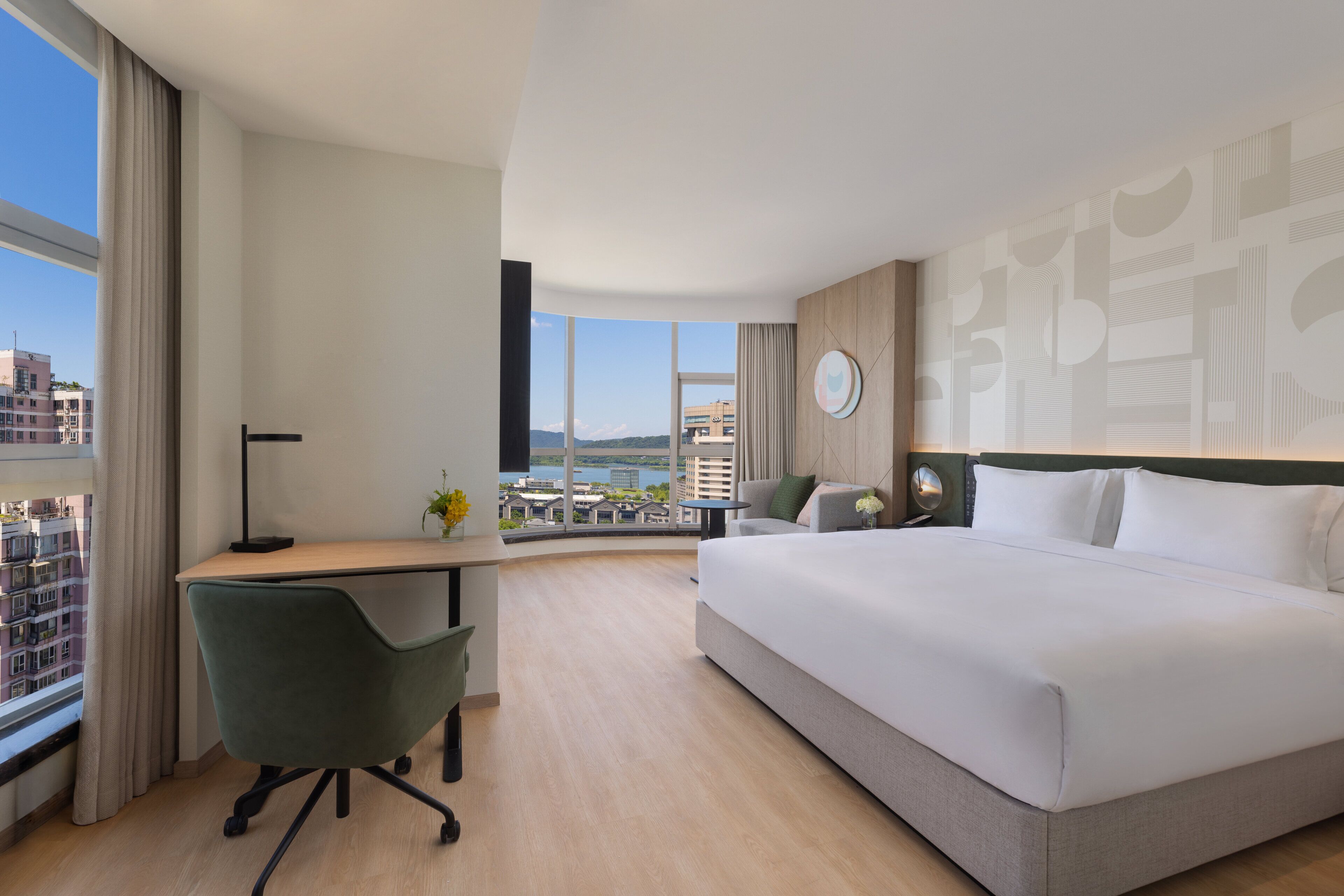 Habitación de hotel con una cama grande, un escritorio, una silla y vistas a la ciudad.