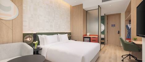 A modern hotel room with a bed, a desk, a chair, and a television.