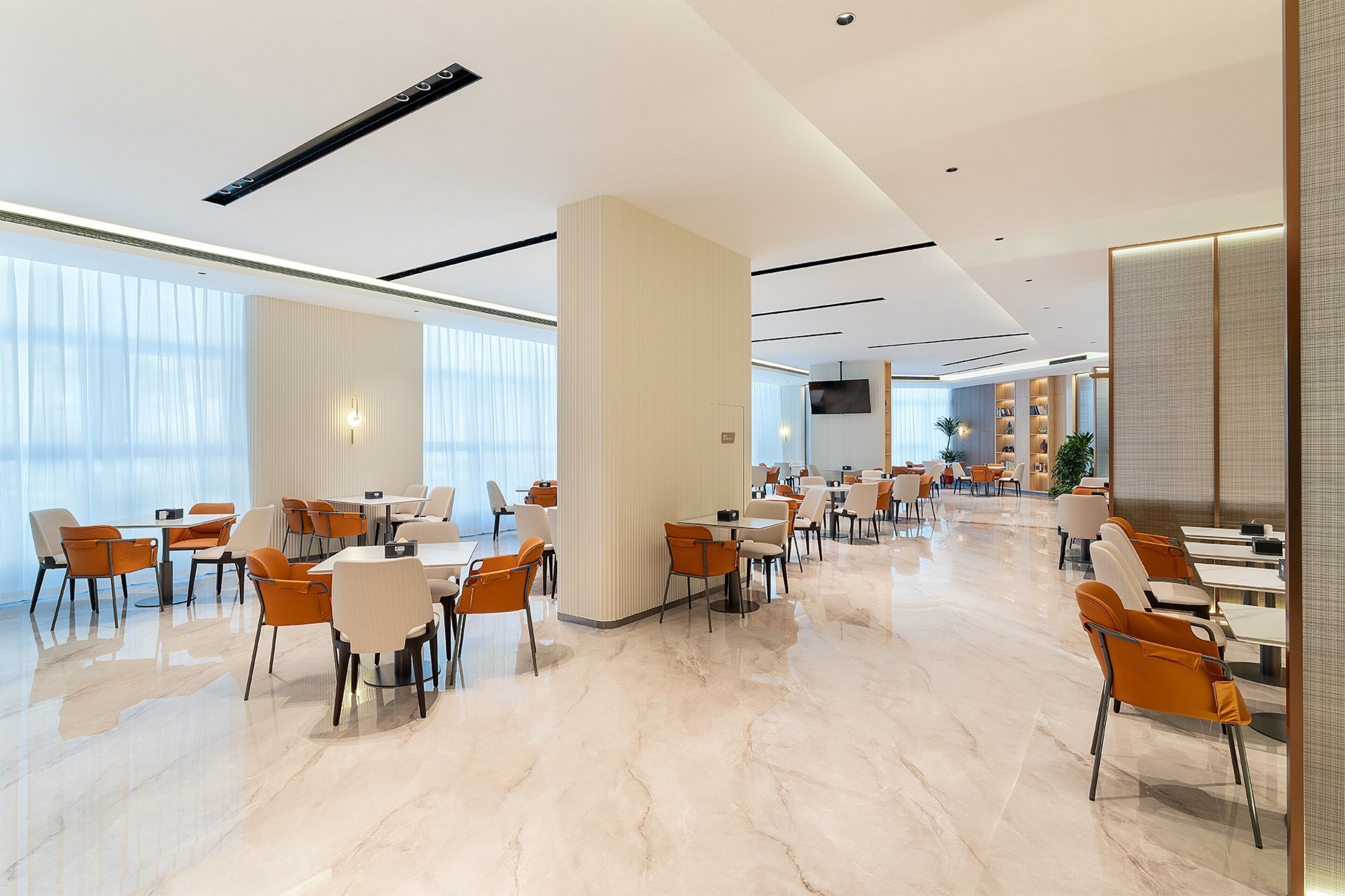 Een ruime hotellobby met moderne inrichting, grote ramen en een schone, gepolijste vloer.