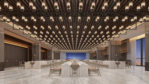 Una amplia sala de conferencias con una larga mesa dispuesta para un banquete, rodeada de sillas, y un techo con luminarias distribuidas uniformemente.