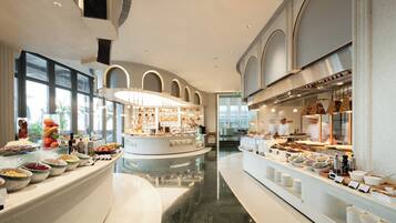 A modern hotel lobby with a central island, large windows, and a kitchen area.