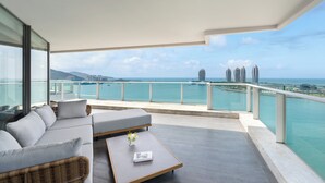 A balcony with a sofa and a coffee table, overlooking a body of water and buildings. - Tiancheng Blemont Hotel Sanya, Vignette Collection by IHG (Sanya)