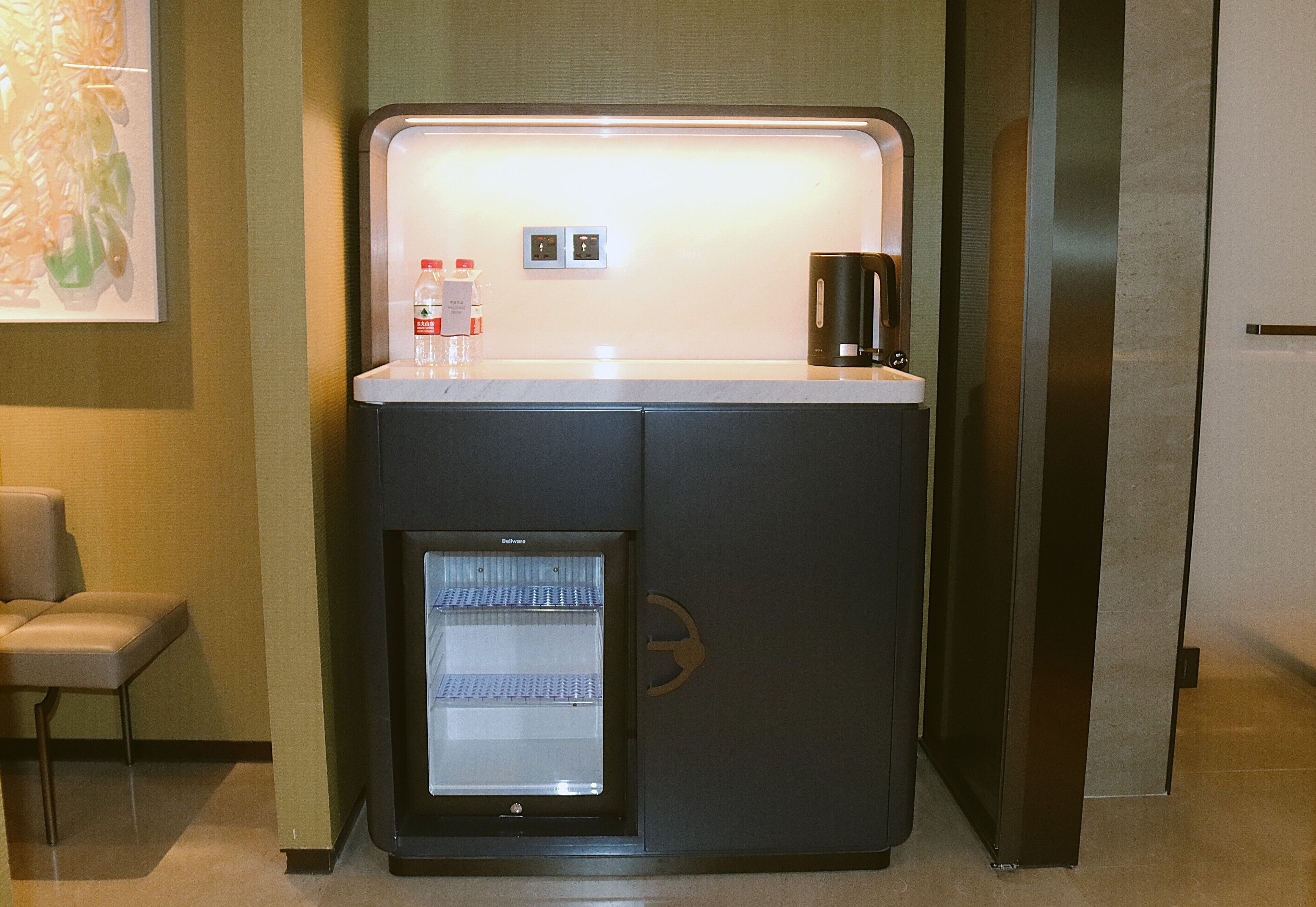 A minibar with a refrigerator, a coffee maker, and a bottle of water.