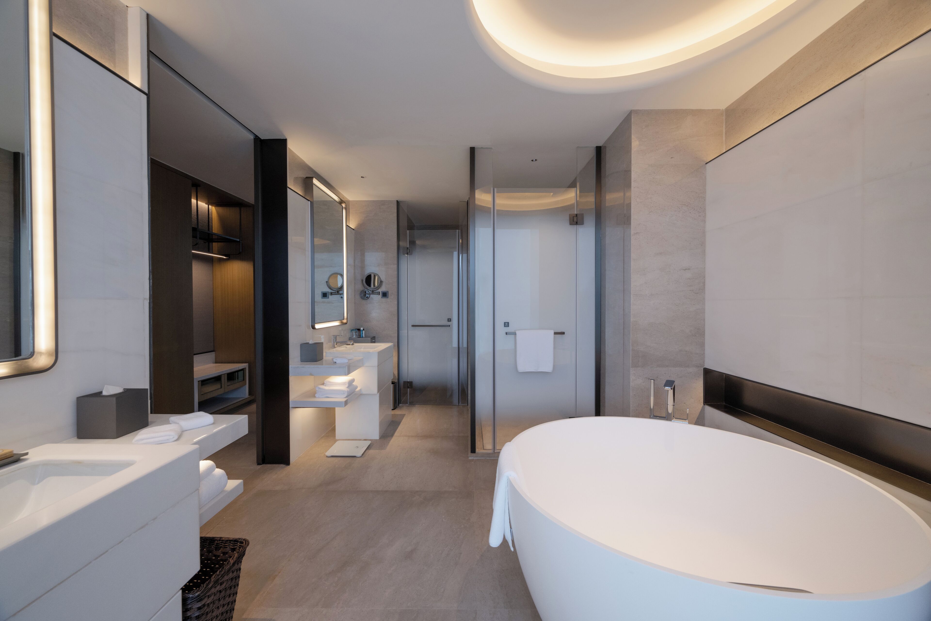 A modern bathroom with a large bathtub, a vanity with a mirror, and a shower area.