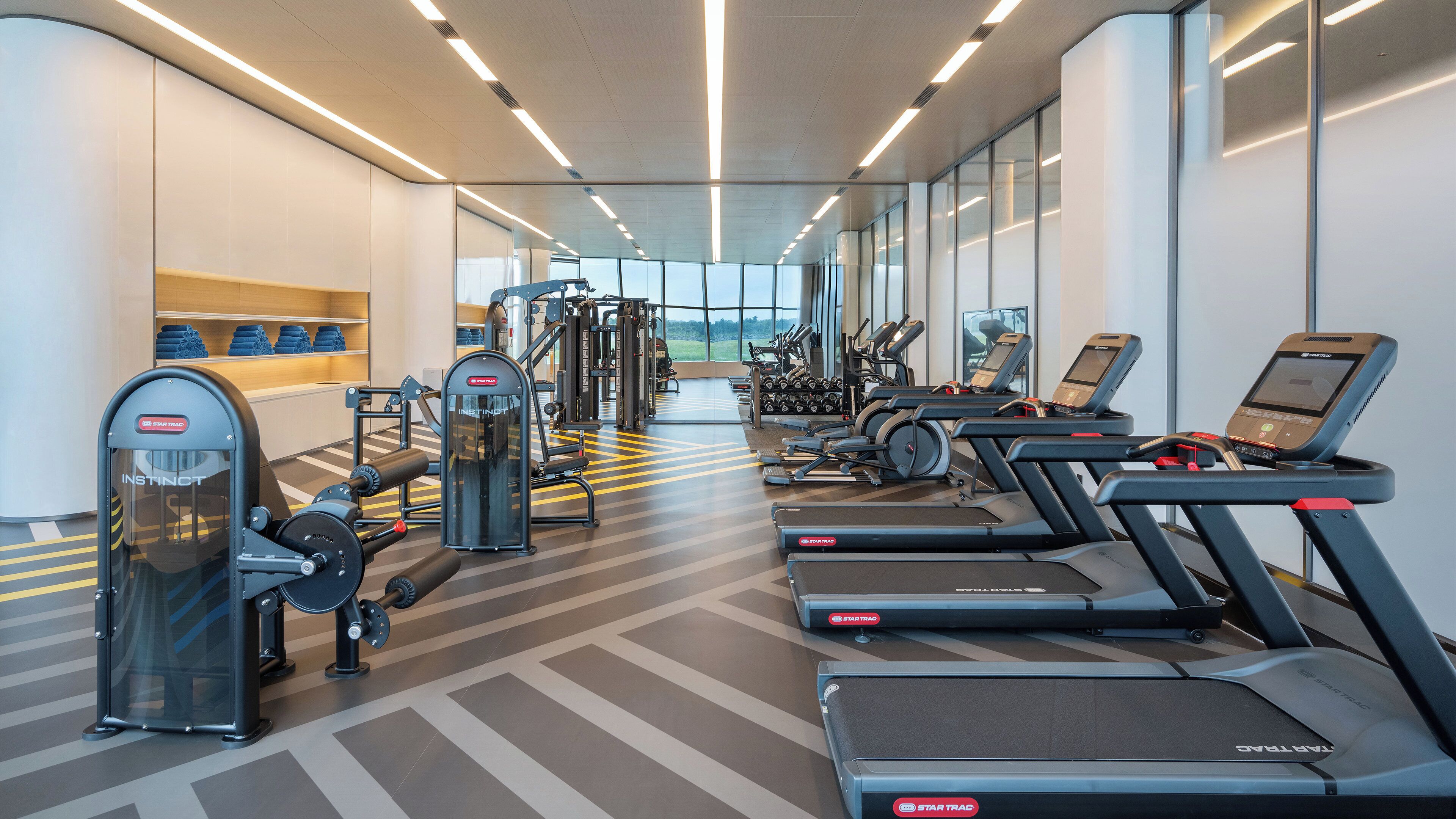 Ein modernes Fitnessstudio mit Laufbändern, Kraftgeräten und einer Spiegelwand.