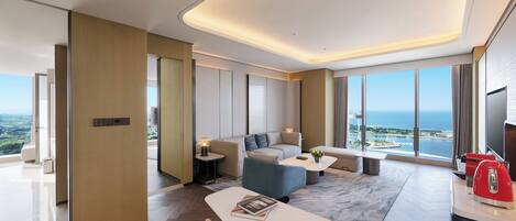 A modern hotel room with a sofa, coffee table, and dining area.