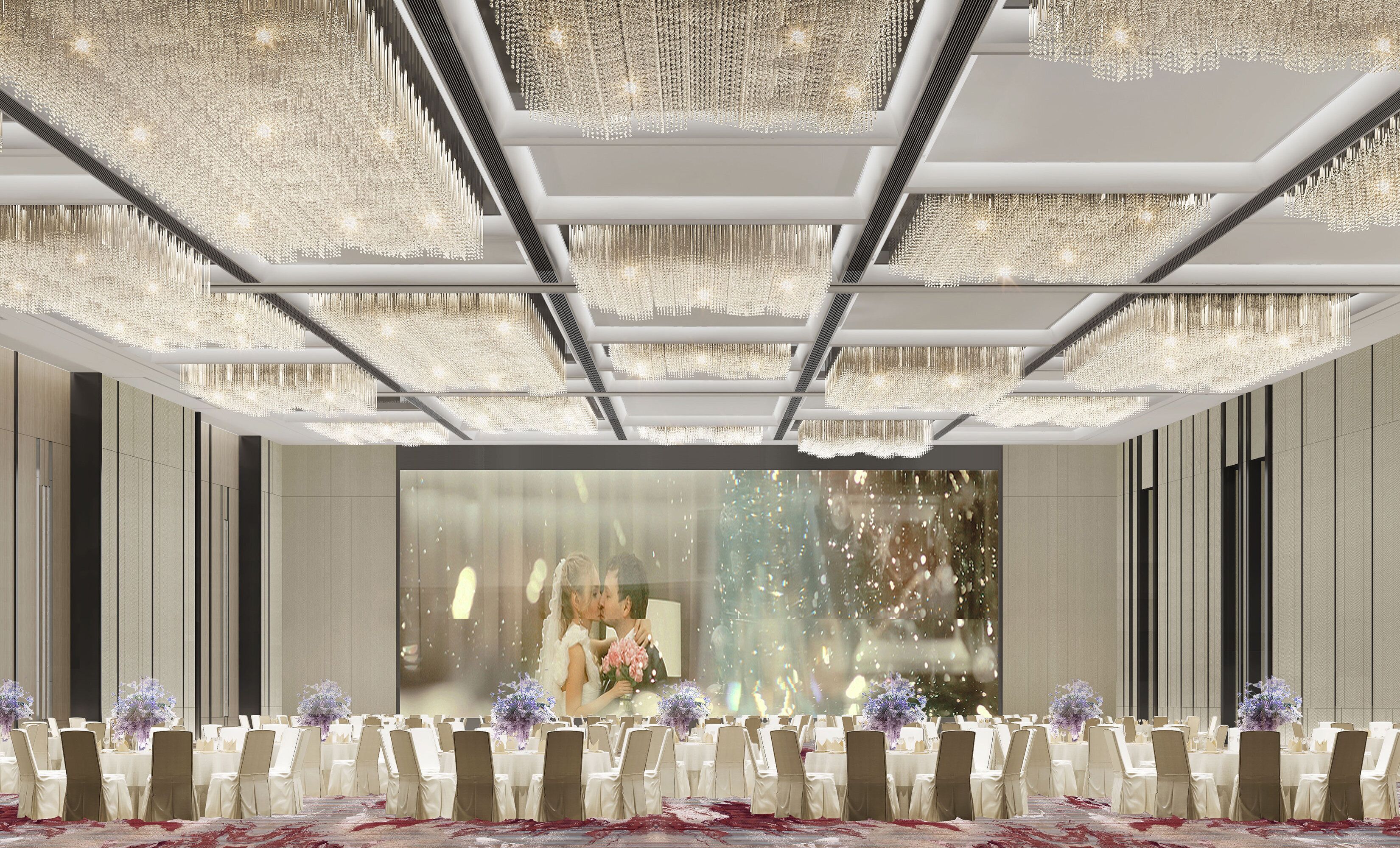 A banquet hall with a high ceiling adorned with chandeliers, white tables with chairs, and a large window with a view of a couple.