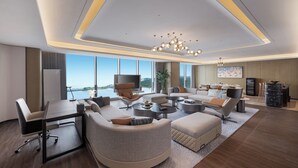A modern hotel room with a large seating area, a dining table, and a view of the cityscape. - Crowne Plaza Weihai Binhai (Weihai)