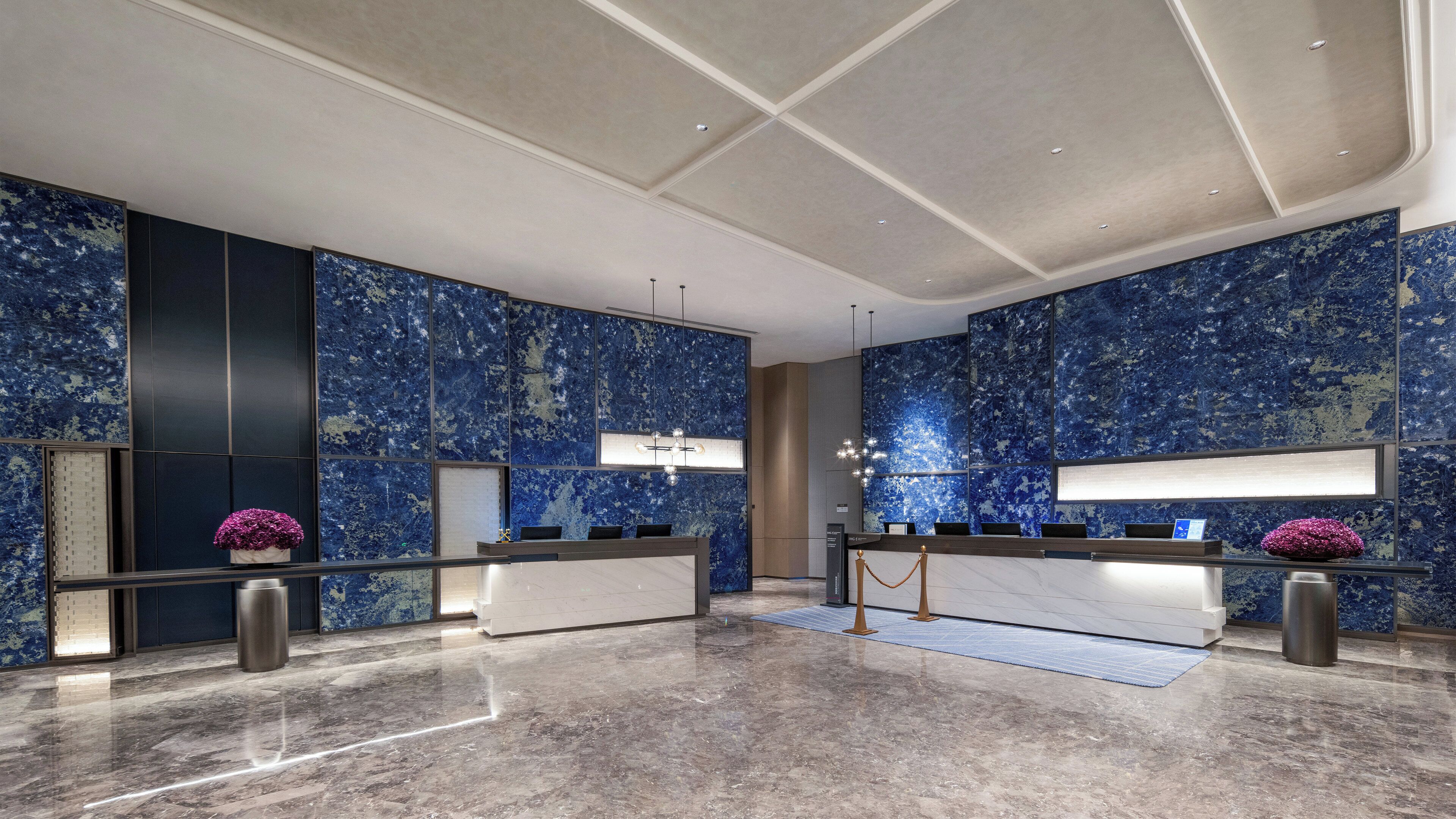 A modern lobby with a marble floor, a reception desk, and blue marble walls.