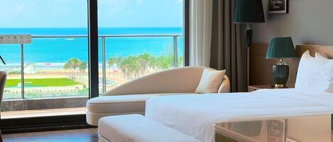 Una habitación de hotel con cama, sofá, escritorio y vista al océano.