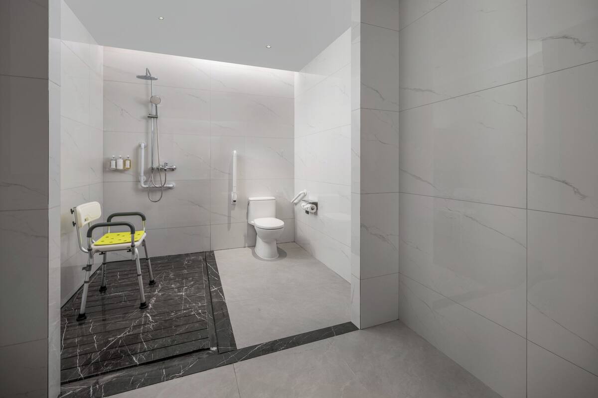 Un baño moderno con ducha, inodoro y una silla accesible para personas en silla de ruedas.