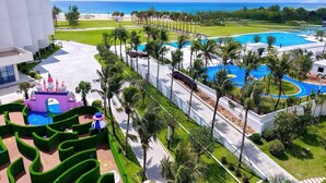 Ein Resort mit großem Poolbereich, Palmen und Meerblick.