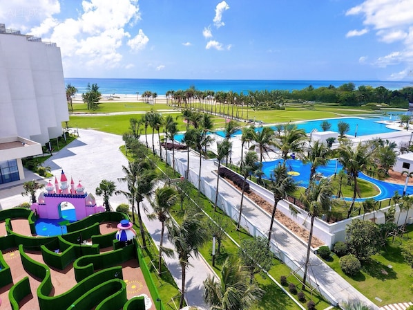 A resort with a large pool area, palm trees, and a view of the ocean.