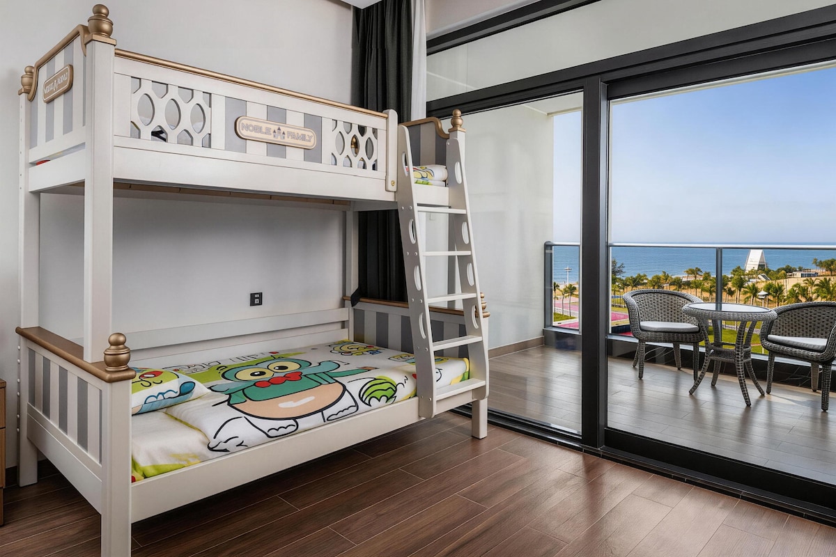 Una cama litera con escalera, una ventana que da a vista al océano y un balcón con sillas de mimbre.