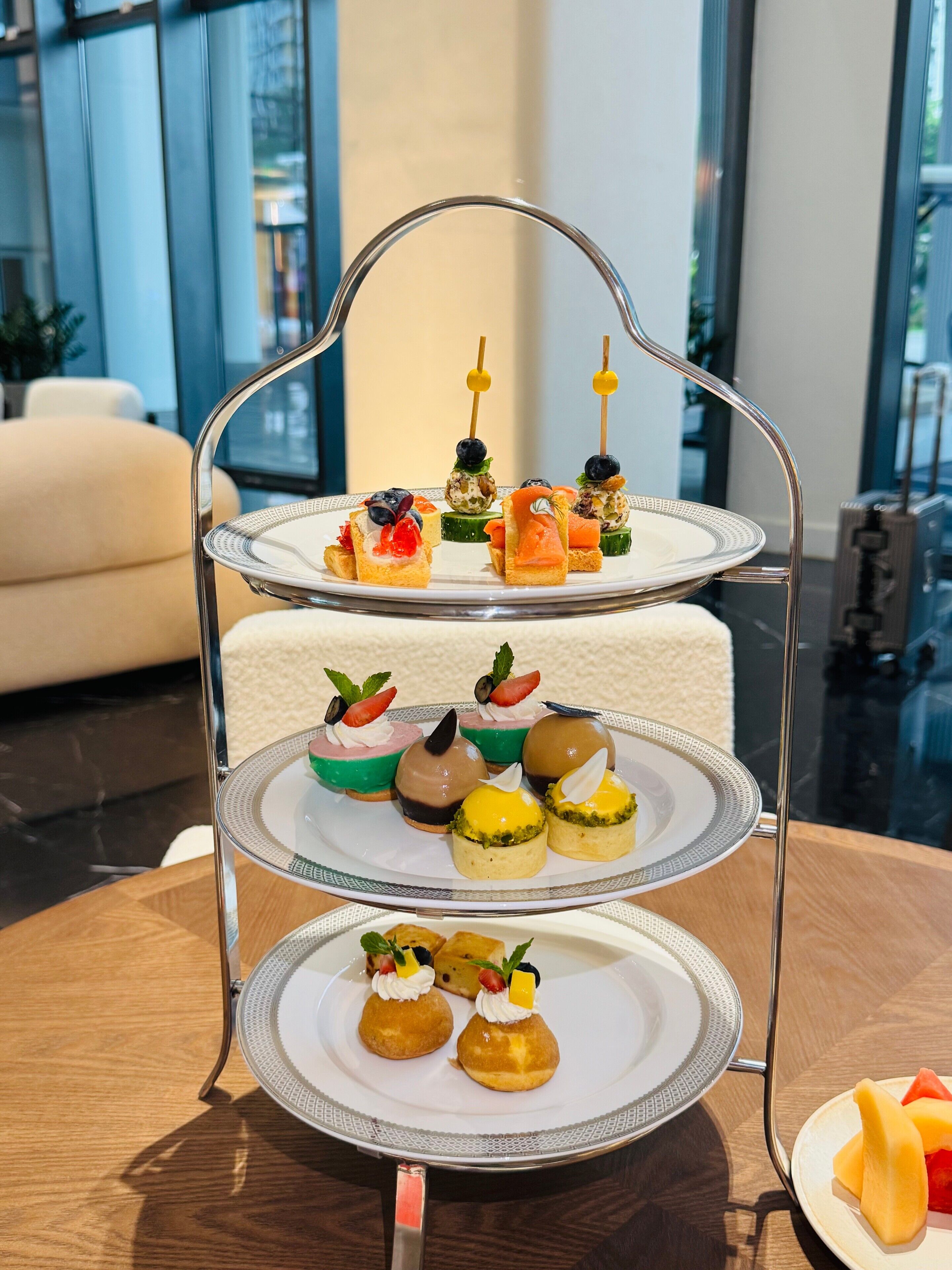 A three-tiered dessert stand with various pastries and fruit tarts.