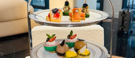 A three-tiered dessert stand with various pastries and fruit tarts.