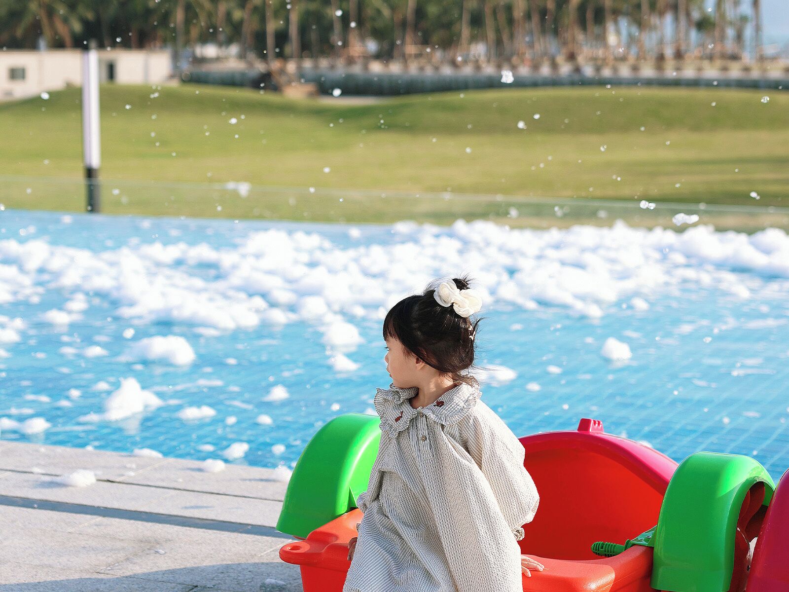 A child playing in a water play area with a pool and inflatable slides.