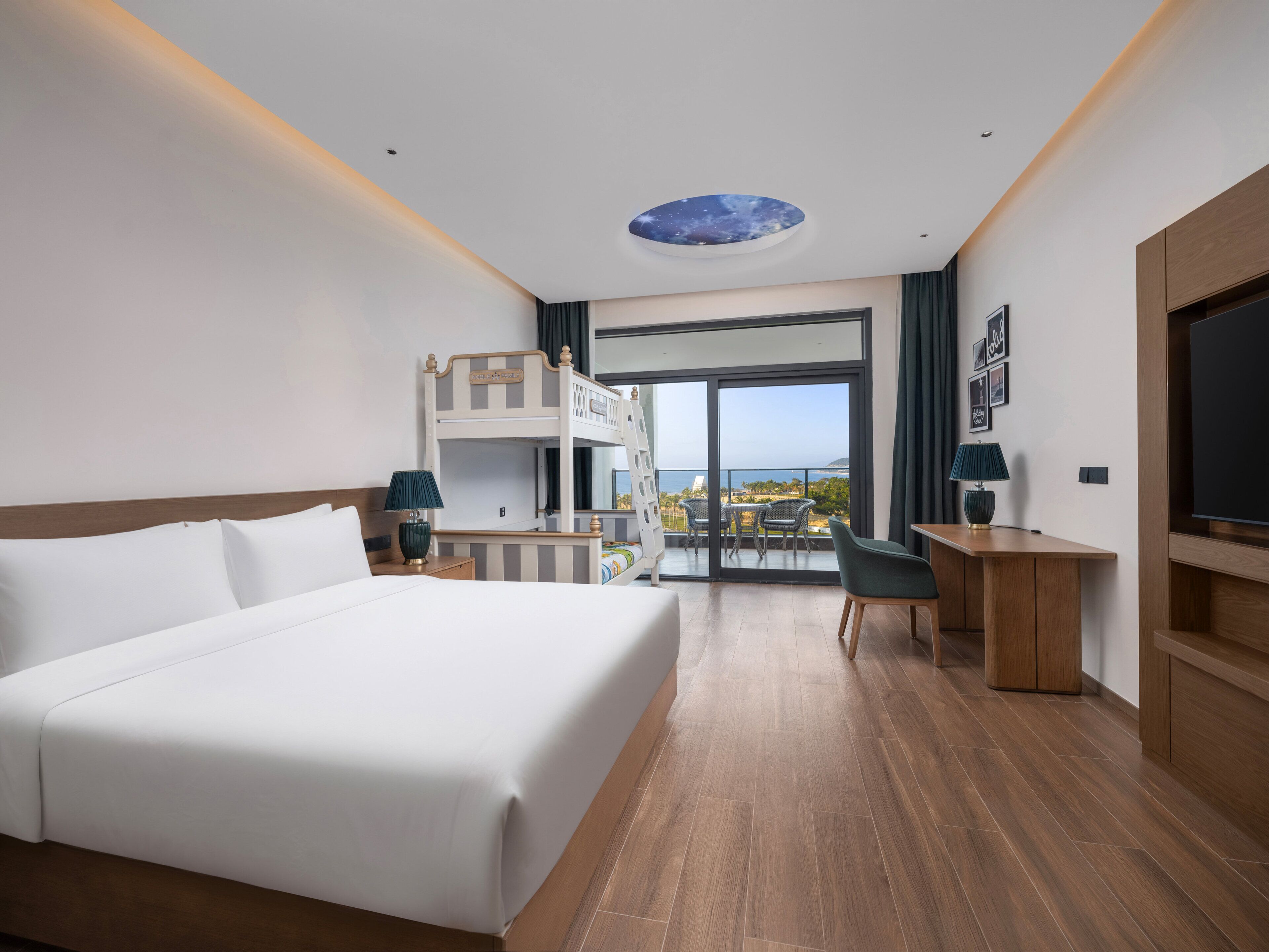 A hotel room with a large bed, a desk, a balcony with a view, and a ceiling with a starry design.
