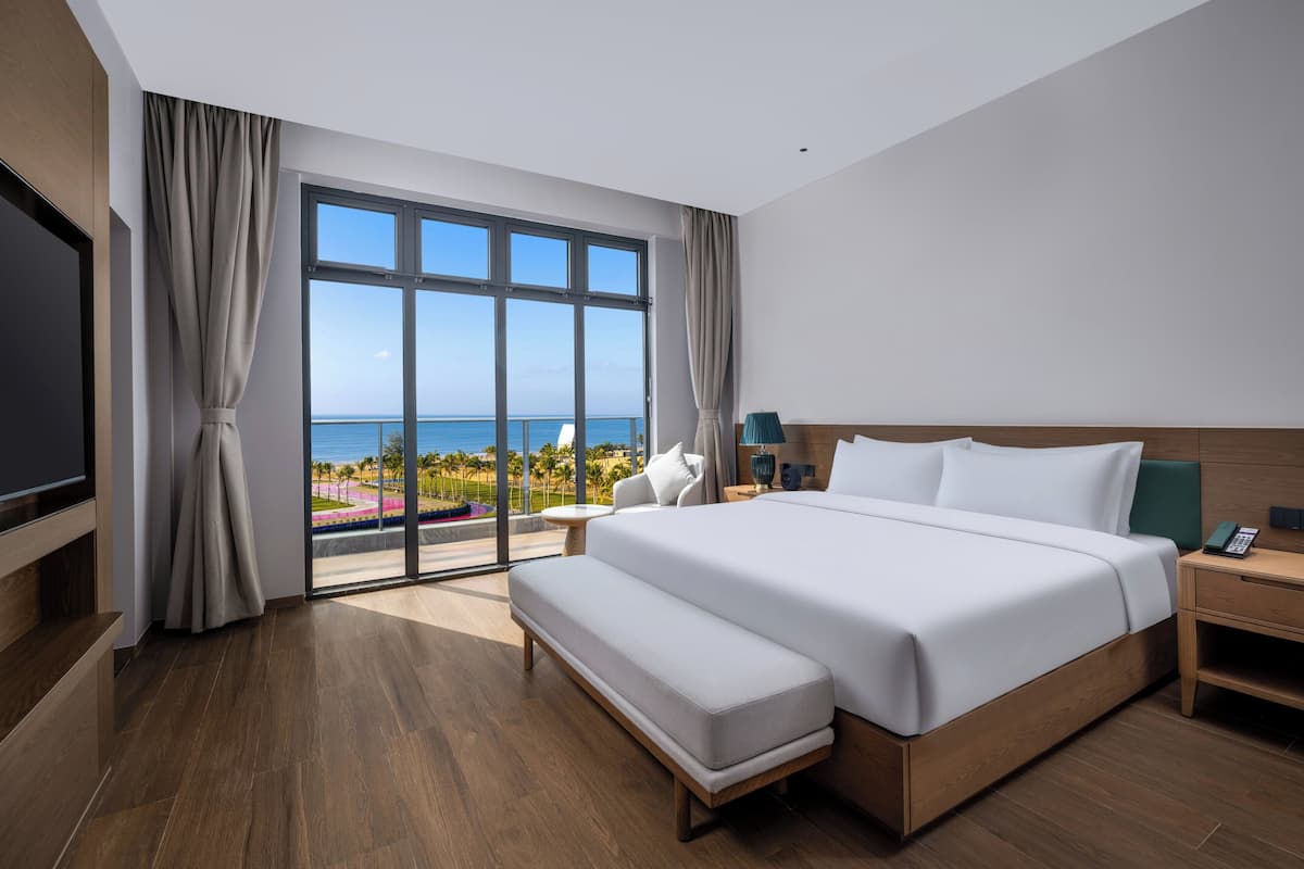 Una habitación de hotel moderna con una cama grande, televisión y vista a la playa.