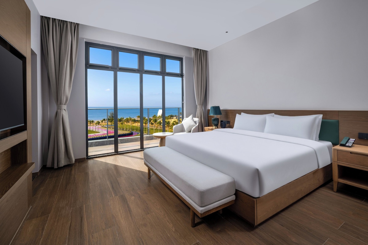 Una habitación de hotel moderna con una cama grande, televisión y vista a la playa.