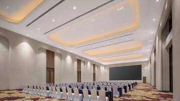 Un salón de conferencias con filas de mesas y sillas, una alfombra estampada e iluminación empotrada.