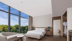 Une chambre d’hôtel moderne avec un grand lit, un canapé, une petite table et un dressing.