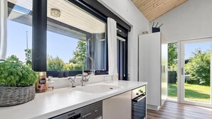 Una cocina moderna con lavavajillas, un fregadero y una ventana con vistas a un jardín.