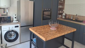 A compact kitchen with a washing machine, a refrigerator, an oven, and a coffee maker. - 1 minute from the beach! Apartment with terrace, ideal for families (La Tremblade)