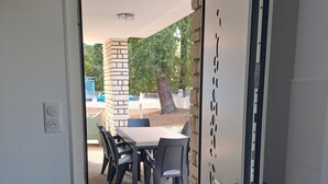 A doorway leading to an outdoor patio with a table and chairs, a doormat, and a stone pillar. - 1 minute from the beach! Apartment with terrace, ideal for families (La Tremblade)