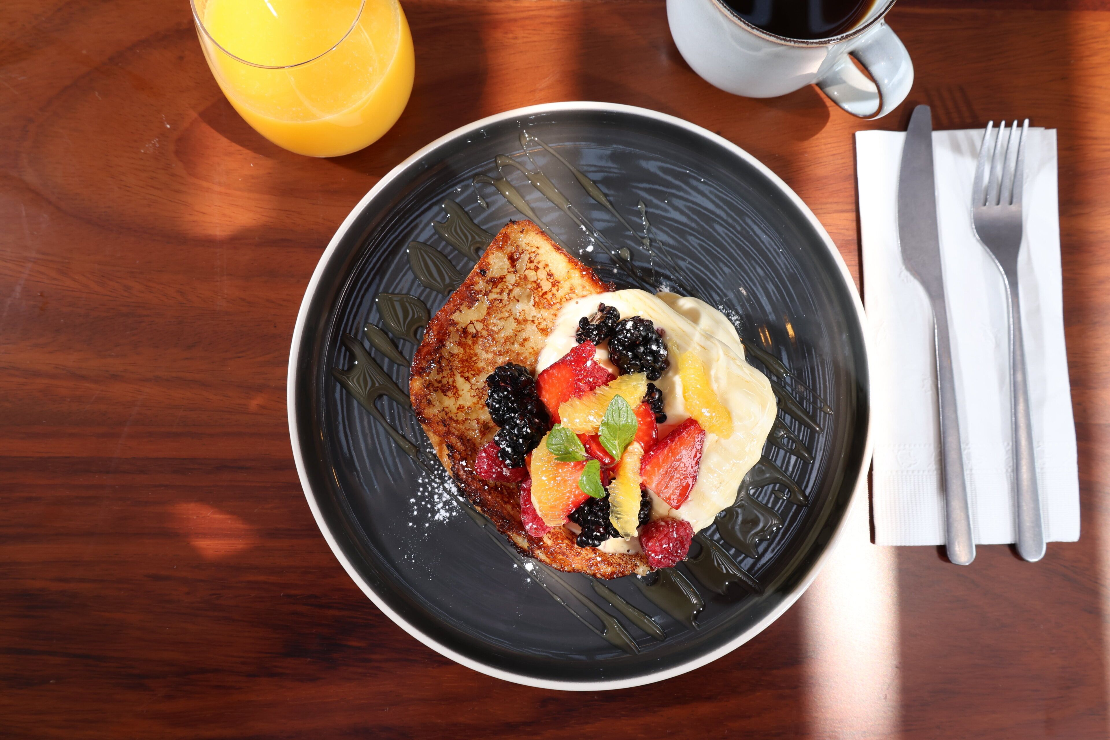 A breakfast plate with toast, fruit, and a beverage on a wooden table.