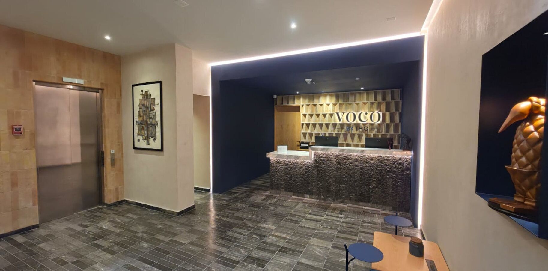 A reception area with a reception desk, a wall-mounted artwork, and a reception counter.