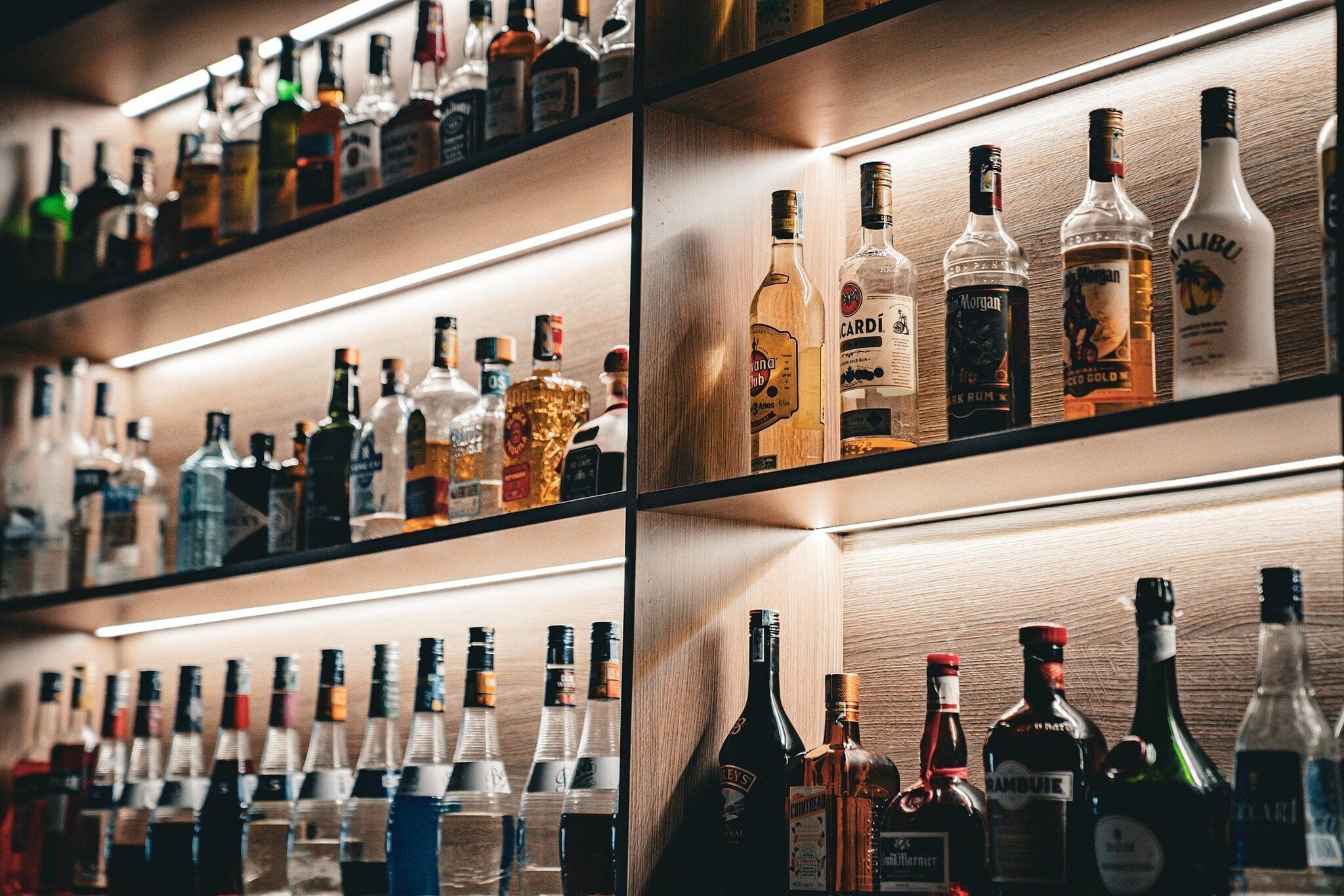 A bar with shelves stocked with various liquor bottles.
