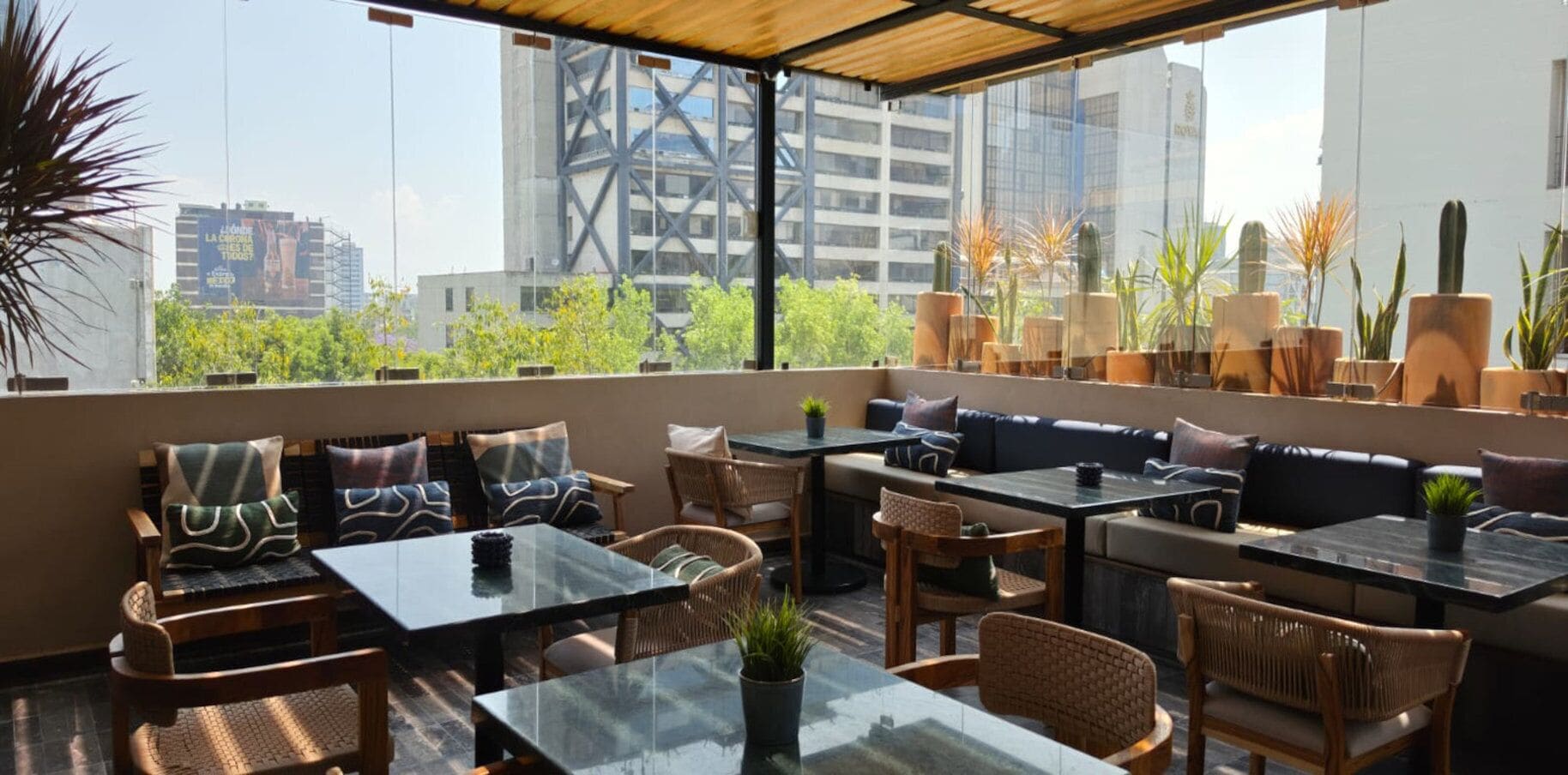 Terraza en la azotea con mobiliario exterior, incluyendo mesas y sillas, y vistas a edificios de la ciudad.