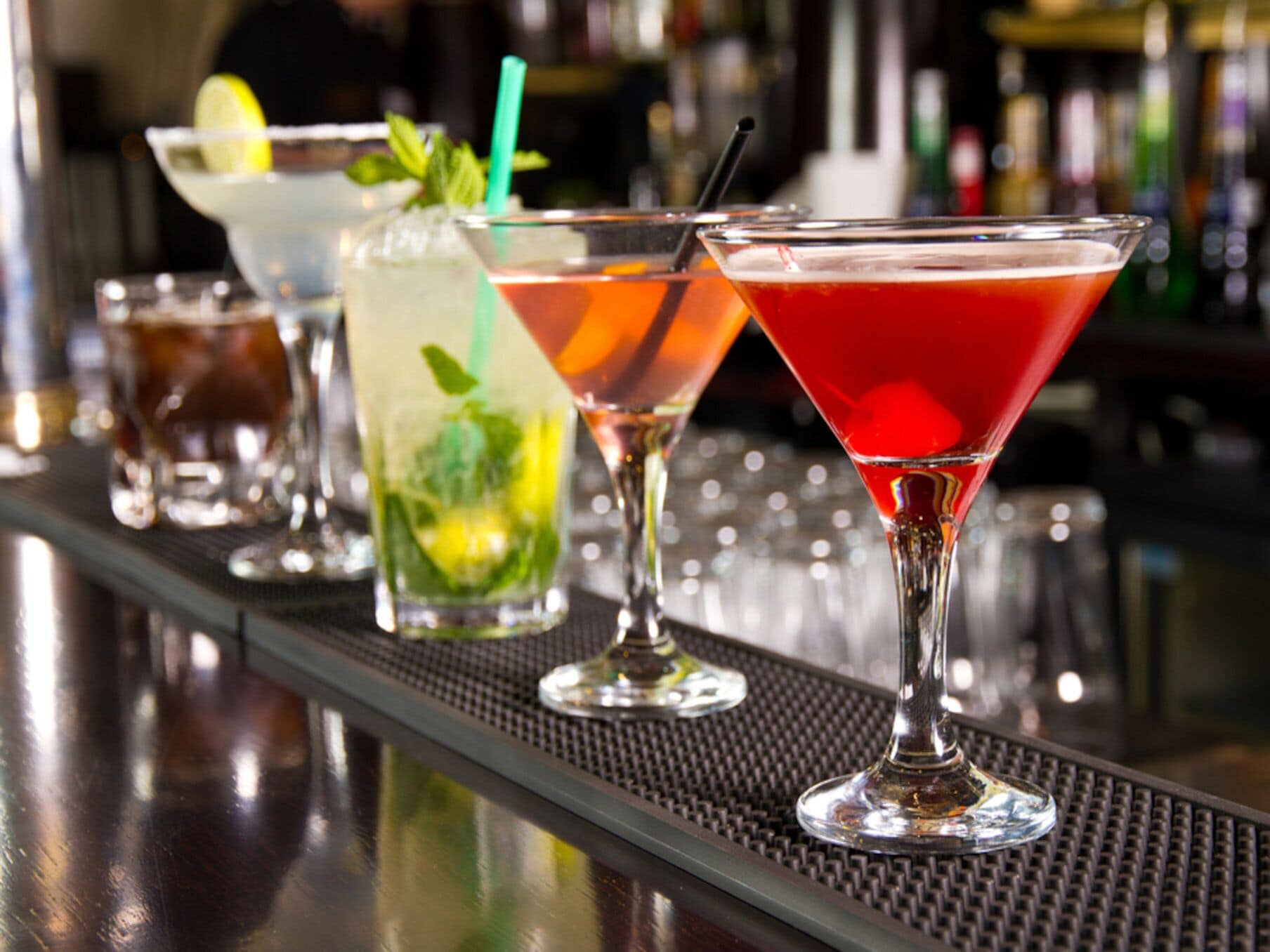 A bar with various drinks in martini glasses.