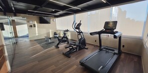 A gym with cardio machines, a treadmill, and a mirrored wall. - voco Ciudad De Mexico Reforma by IHG (Mexico City)