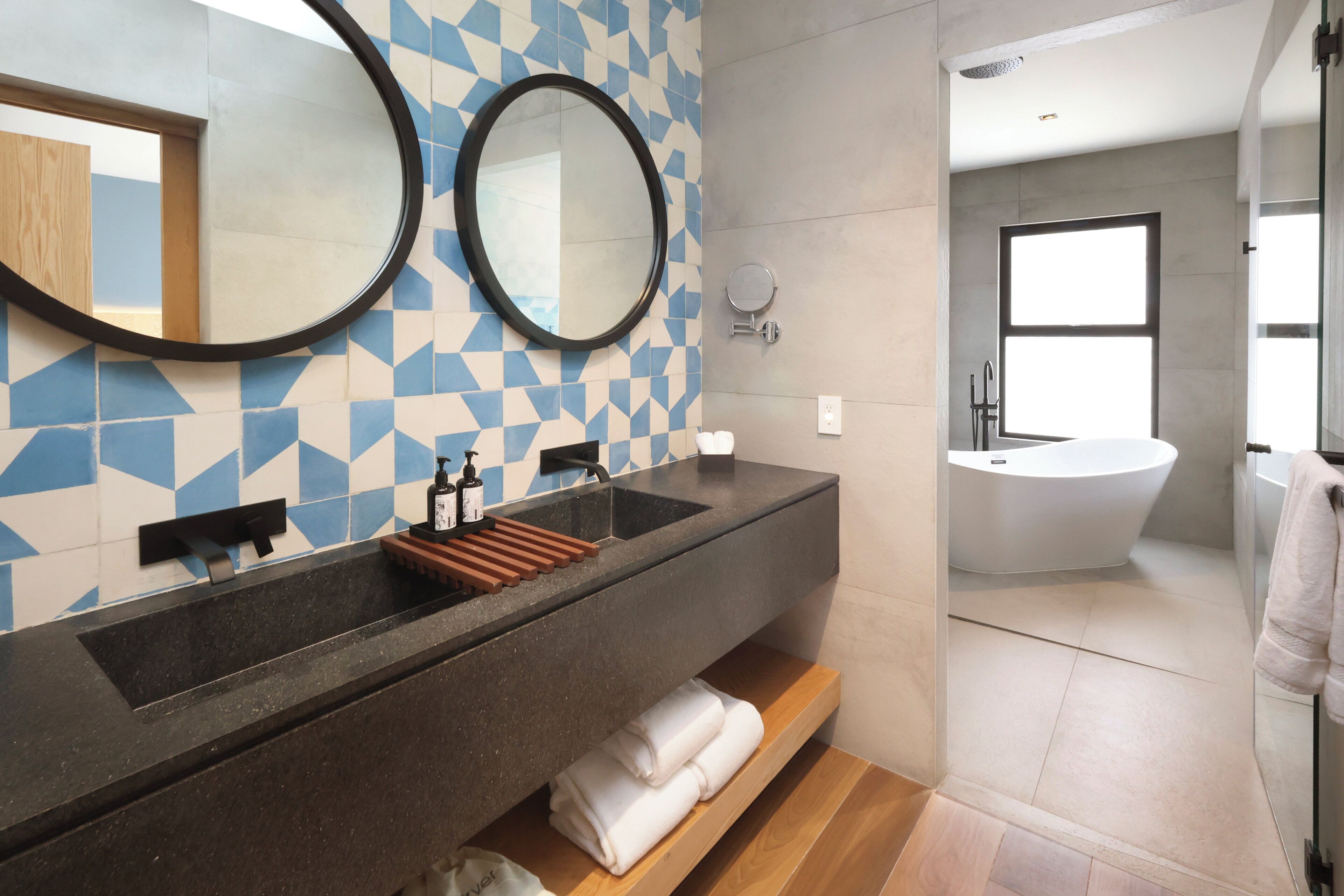 A modern bathroom with a large mirror, a sink, and a bathtub.