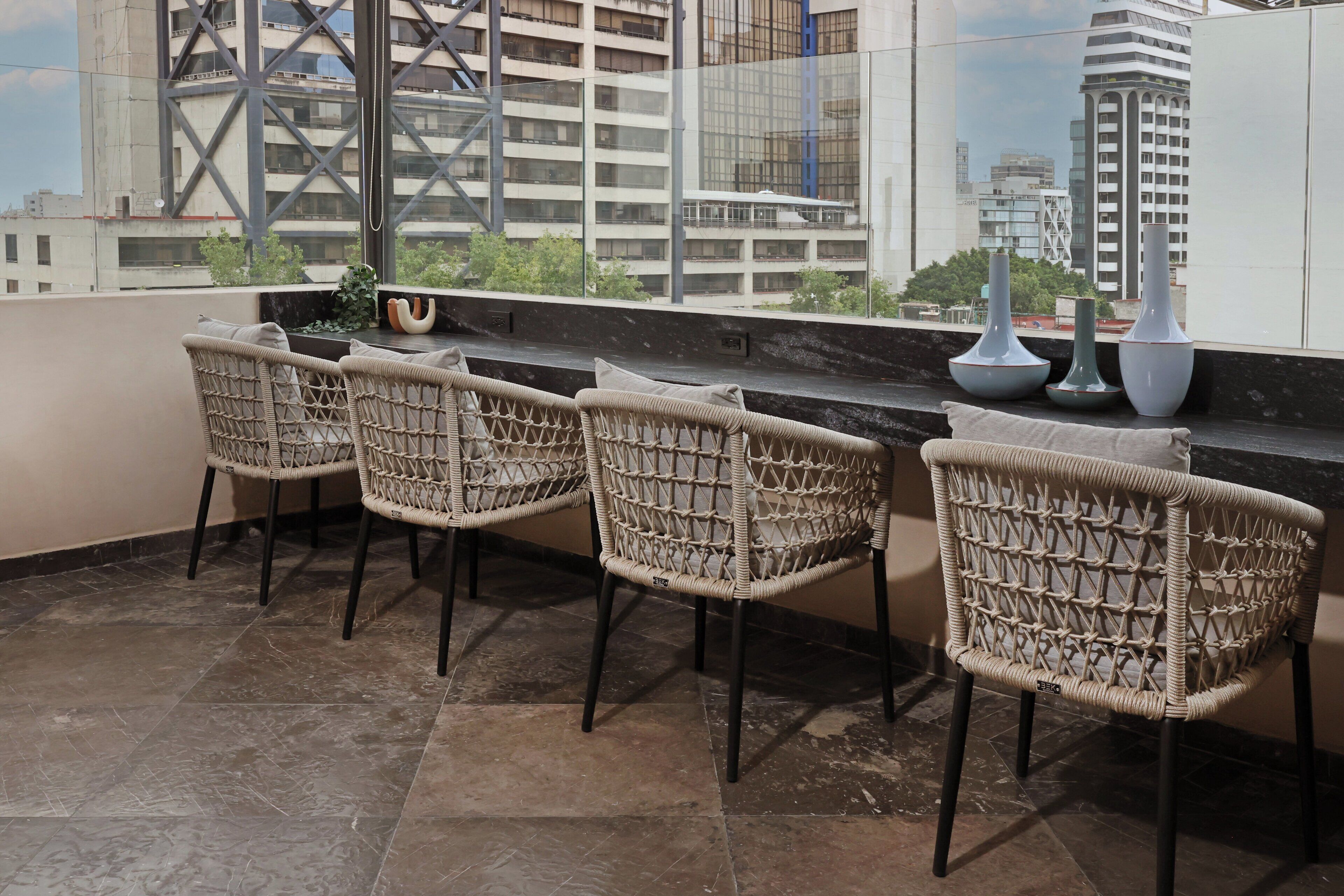 A balcony with wicker chairs, a marble floor, and a view of city buildings.