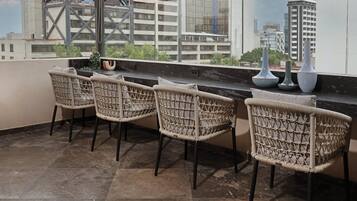 A balcony with wicker chairs, a marble floor, and a view of city buildings.