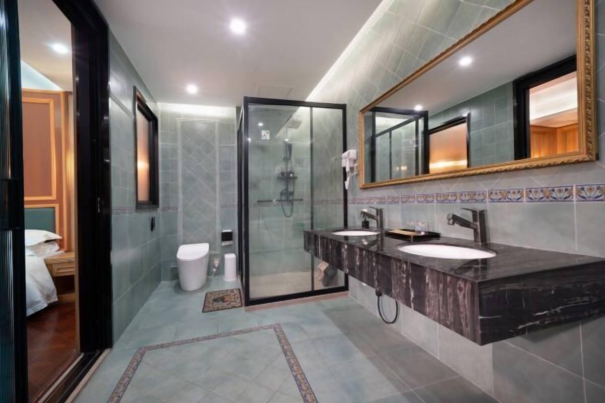 A modern bathroom with a glass shower enclosure, dual sinks, and a large mirror.