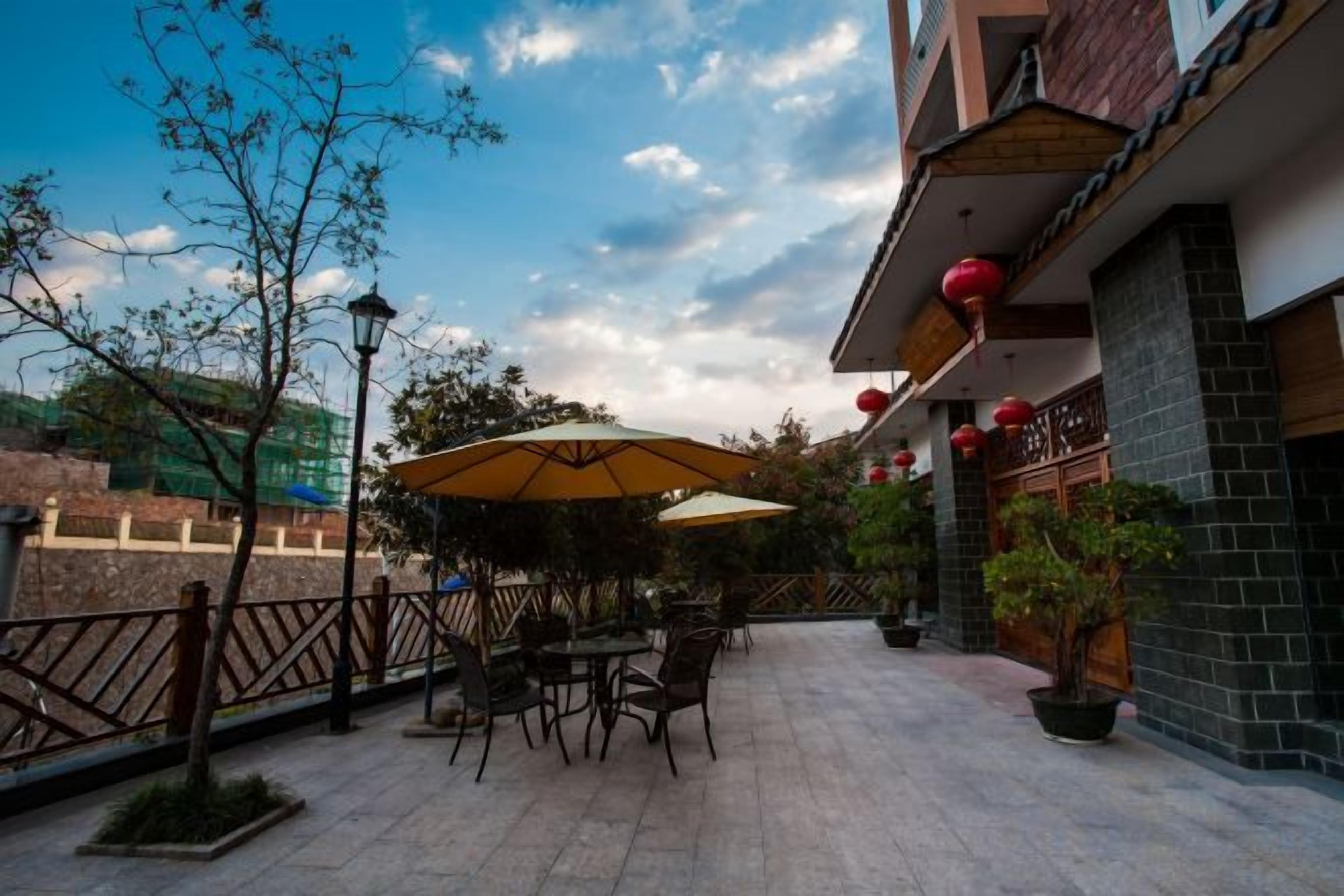 An outdoor patio with tables and chairs, a street view, and a building with red lanterns.