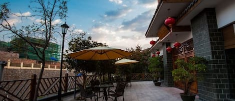An outdoor patio with tables and chairs, a street view, and a building with red lanterns.