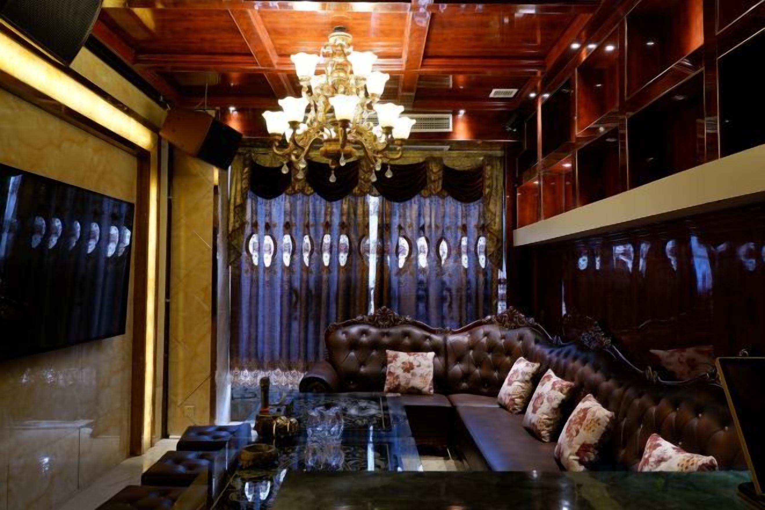 A room with a large, ornate sofa, a glass coffee table, and a chandelier.