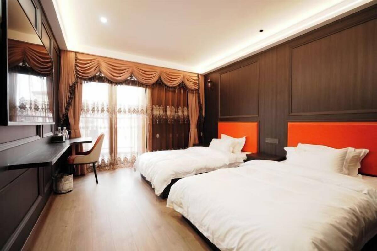 A hotel room with two beds, a desk, and a chair.