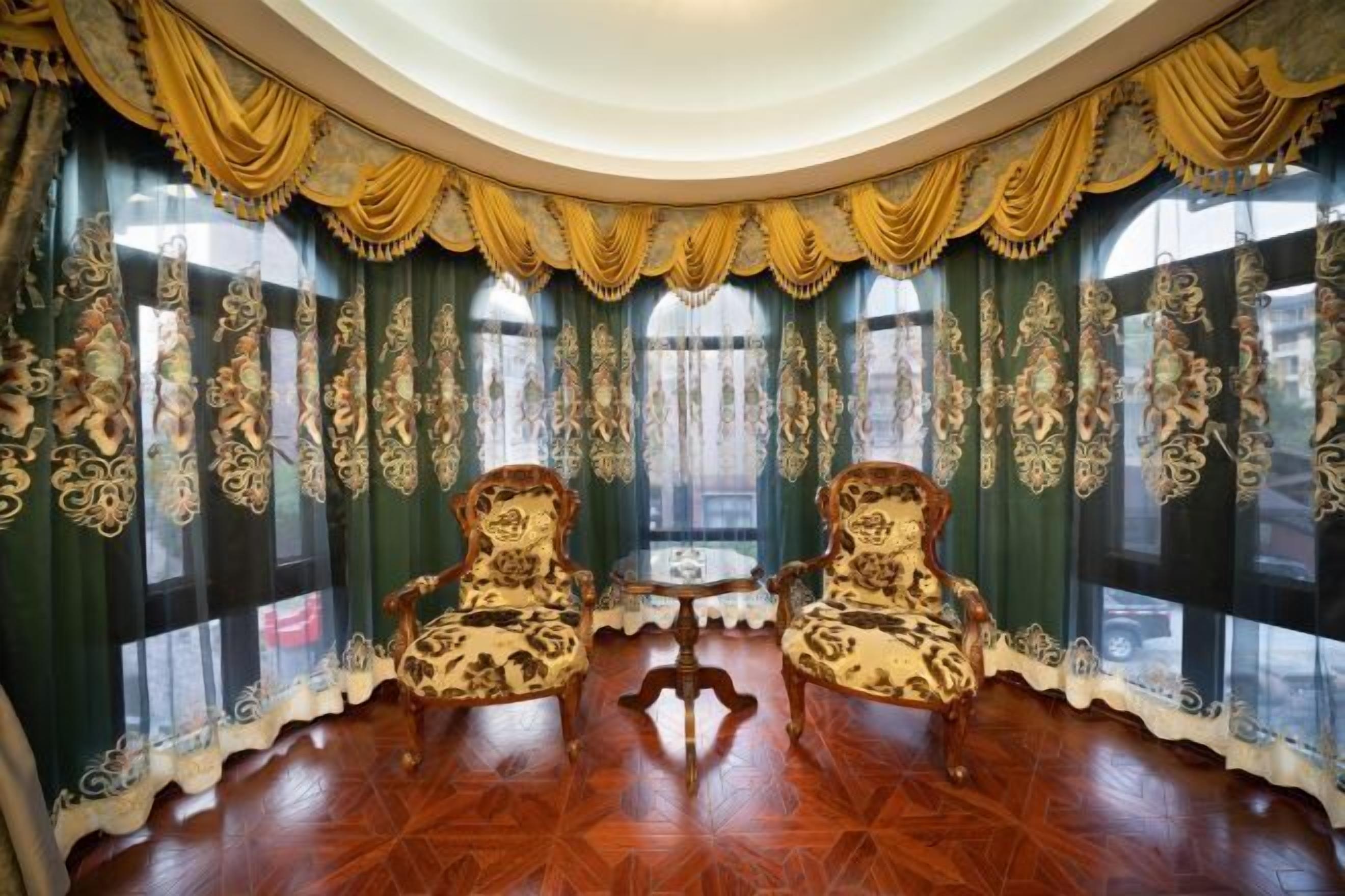 A room with ornate curtains, two chairs, and a small table.