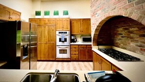 A kitchen with wooden cabinets, a stainless steel refrigerator, an oven, a microwave, and a brick oven. - Pacific Dreams at Woodland Hills Distinguished 8 Br 6 5 BA Residence With Pool and Spa Sleeps 16 (Calabasas)